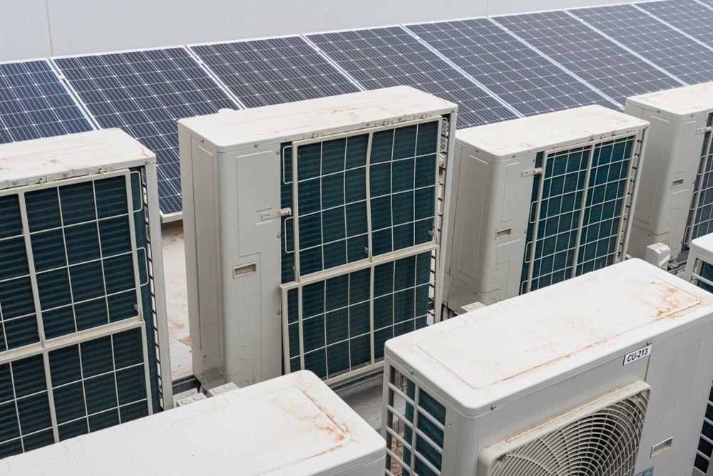 Solar Panels Atop a Building With Multiple White Air Conditioning — Brian Williams Electrical Air Solar in Noosa, QLD