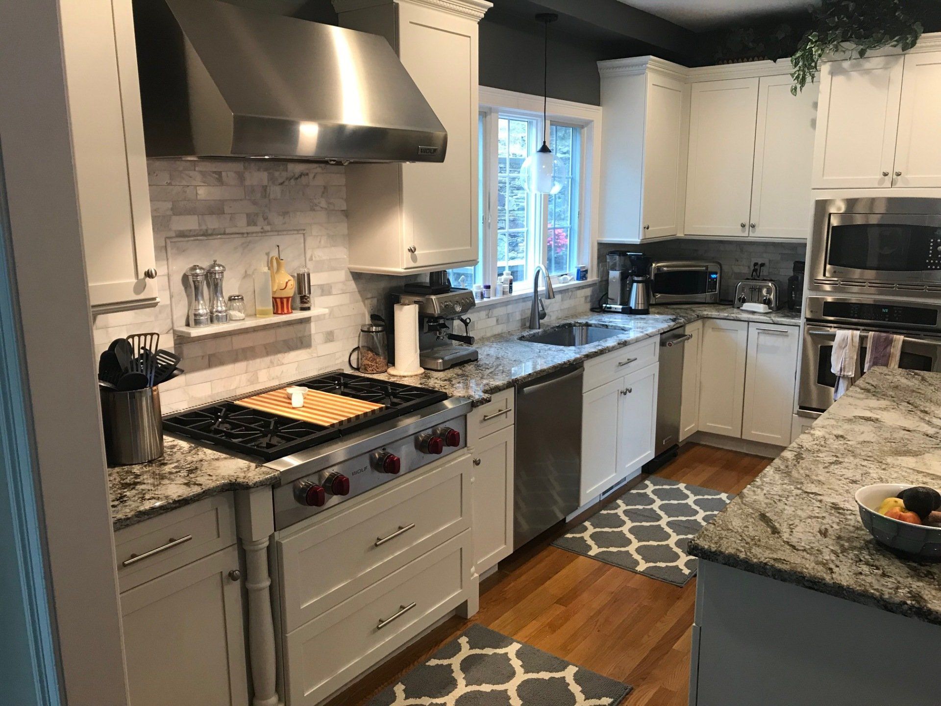 White kitchen with stainless steel appliances and gray countertops.