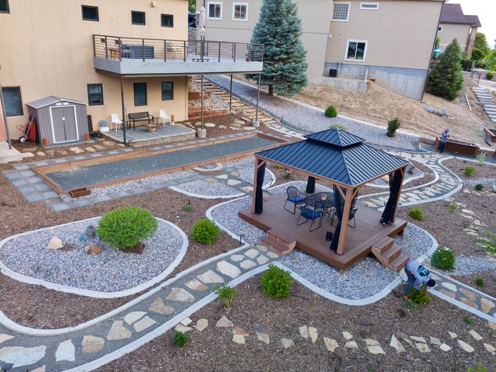 Aerial view of a backyard with a gazebo, stone pathways, and a deck connected to a house.