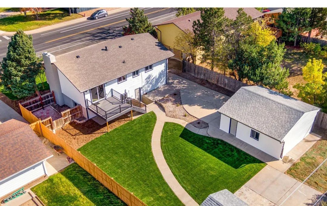 Aerial view of a two-story white house with a detached garage and a green lawn.