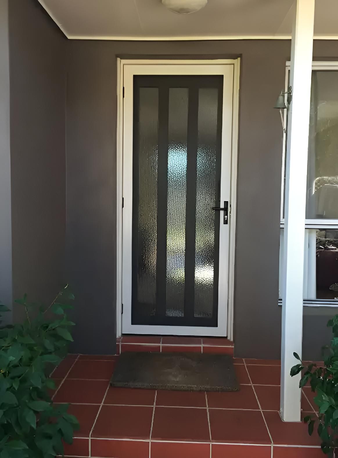 A White Door With a Black Frame is on a Porch — Clearshield Security Screens in Shellharbour, NSW