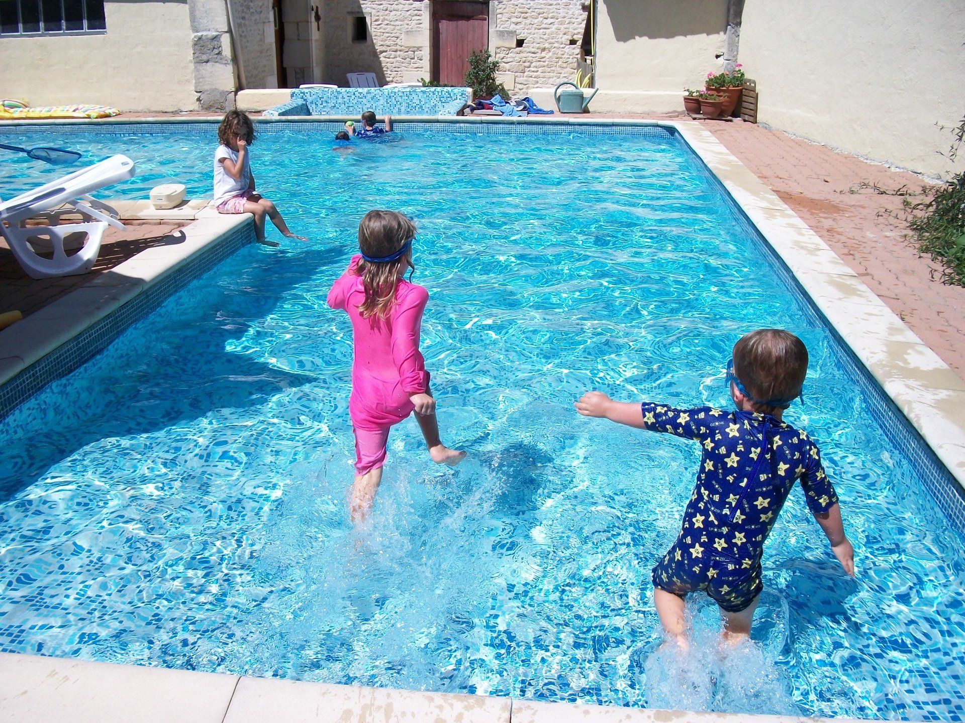 children running into a shallow swimming pool