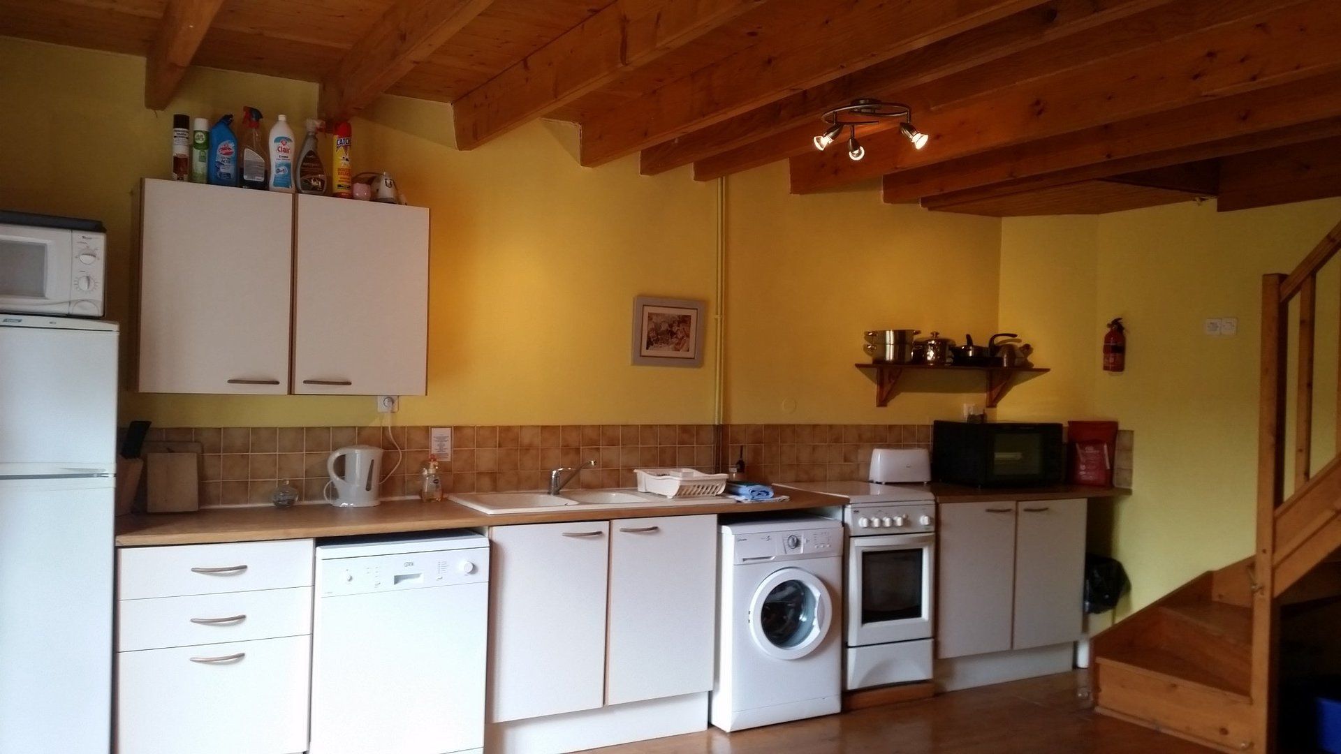 eenvoudige keuken met witte wasmachine en wit gasfornuis en werkblad met houteffect