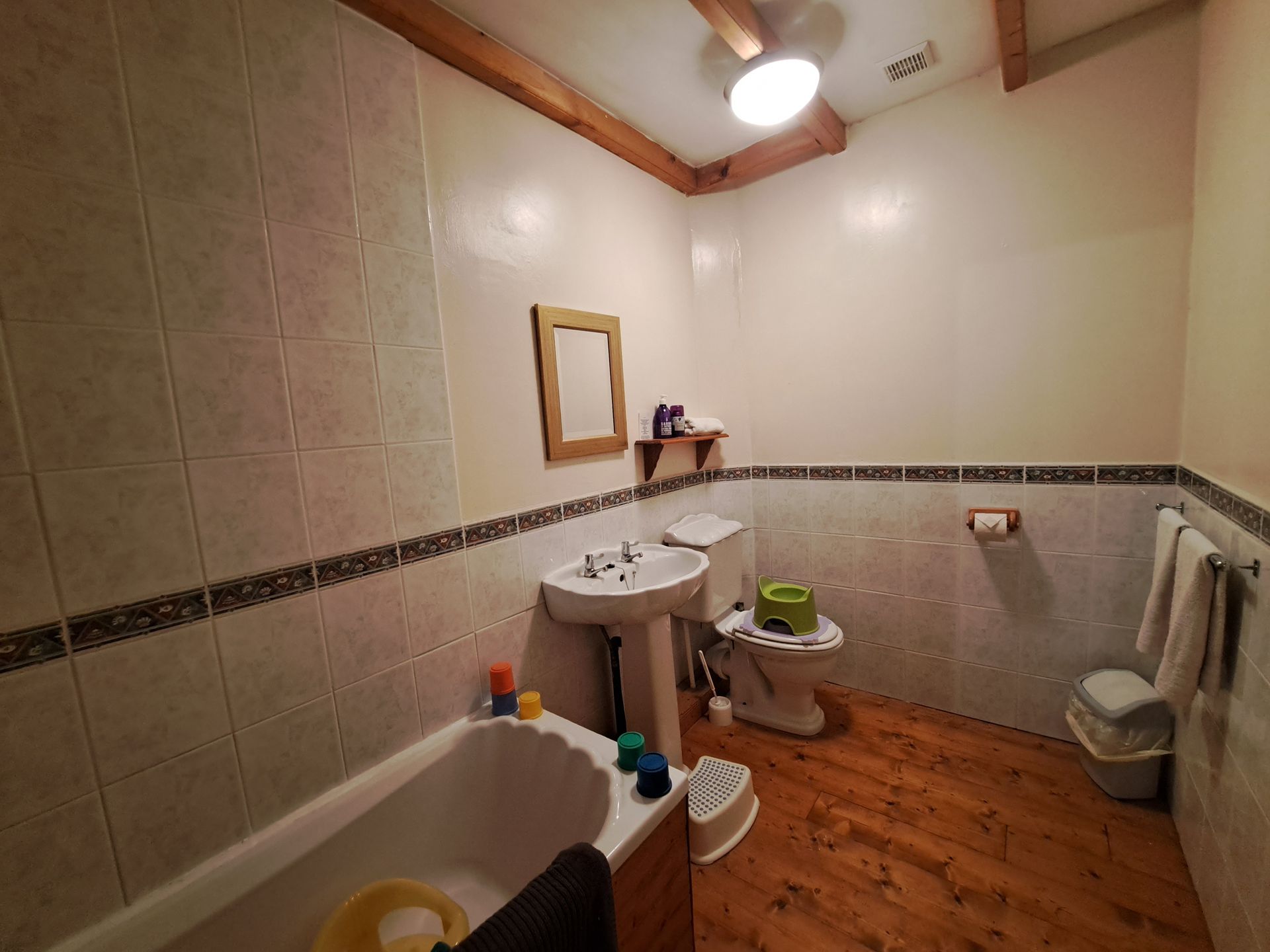 badkamer met houten vloer, witte badkamer, witte wastafel en wit toilet