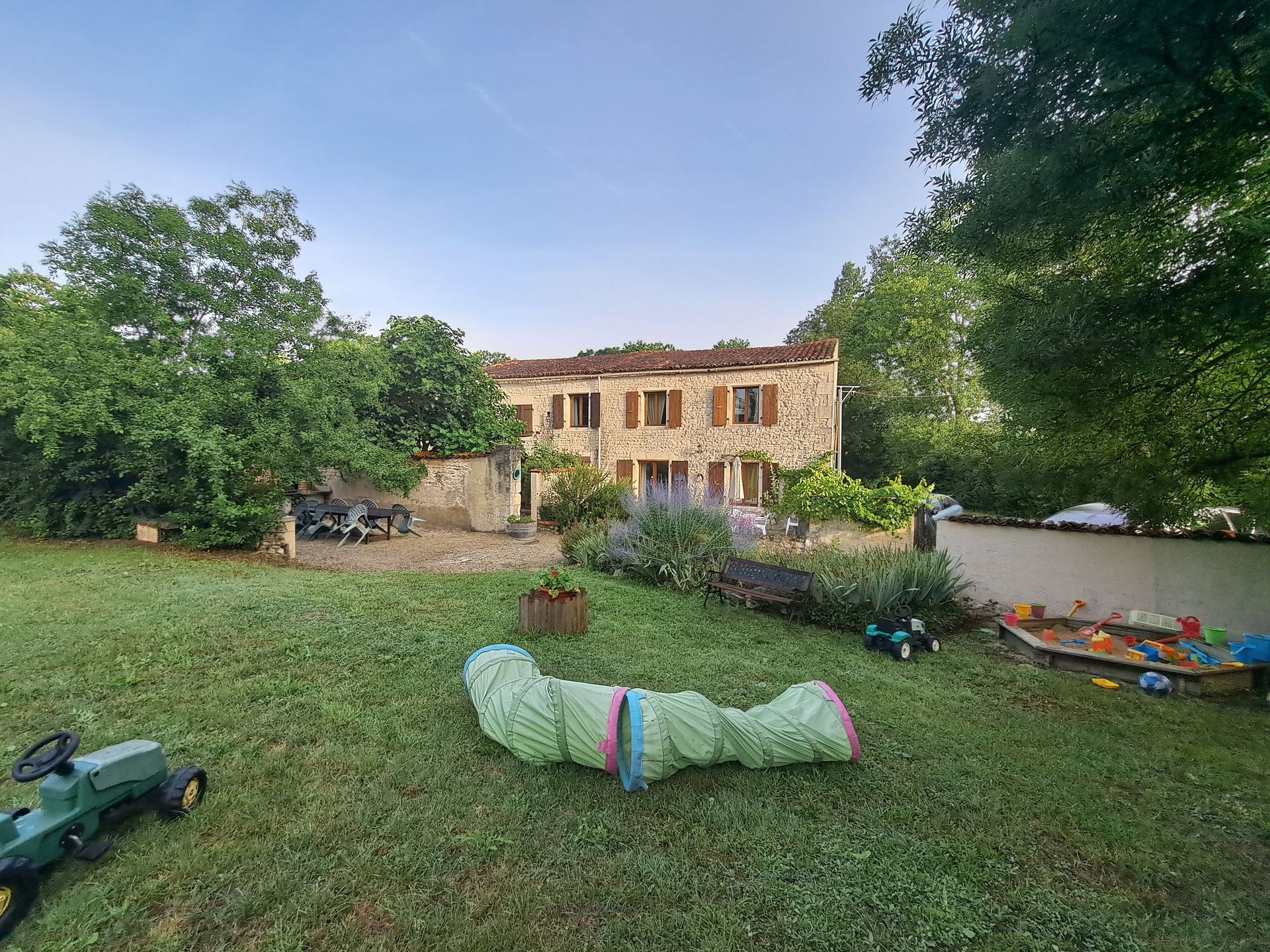 Speeltuin met gras en kinderspeelgoed voor een Frans stenen huisje