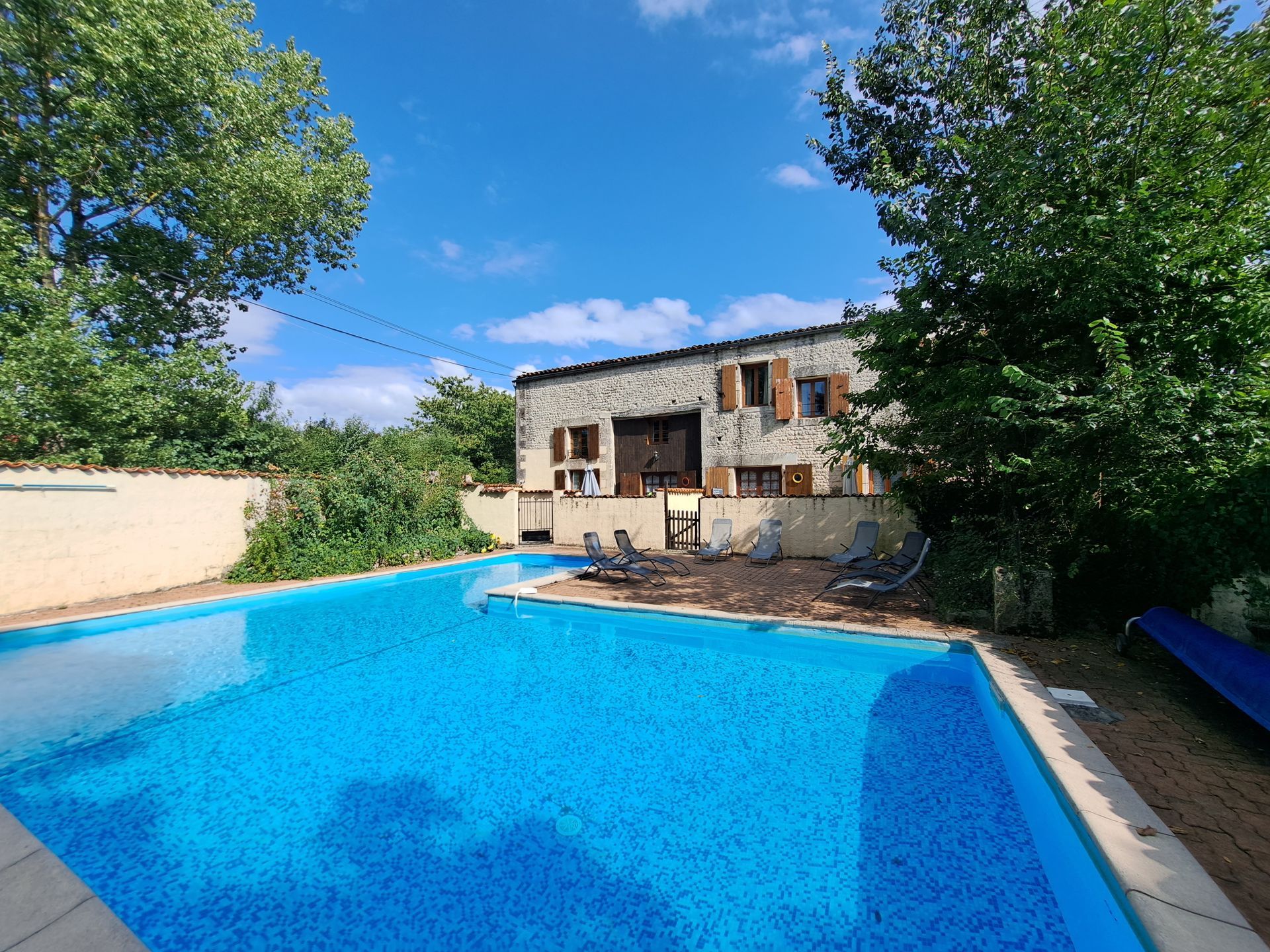 L shaped swimming pool with stone cottage