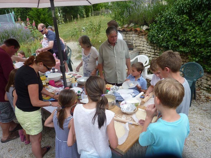 Families making pizzas around a table
