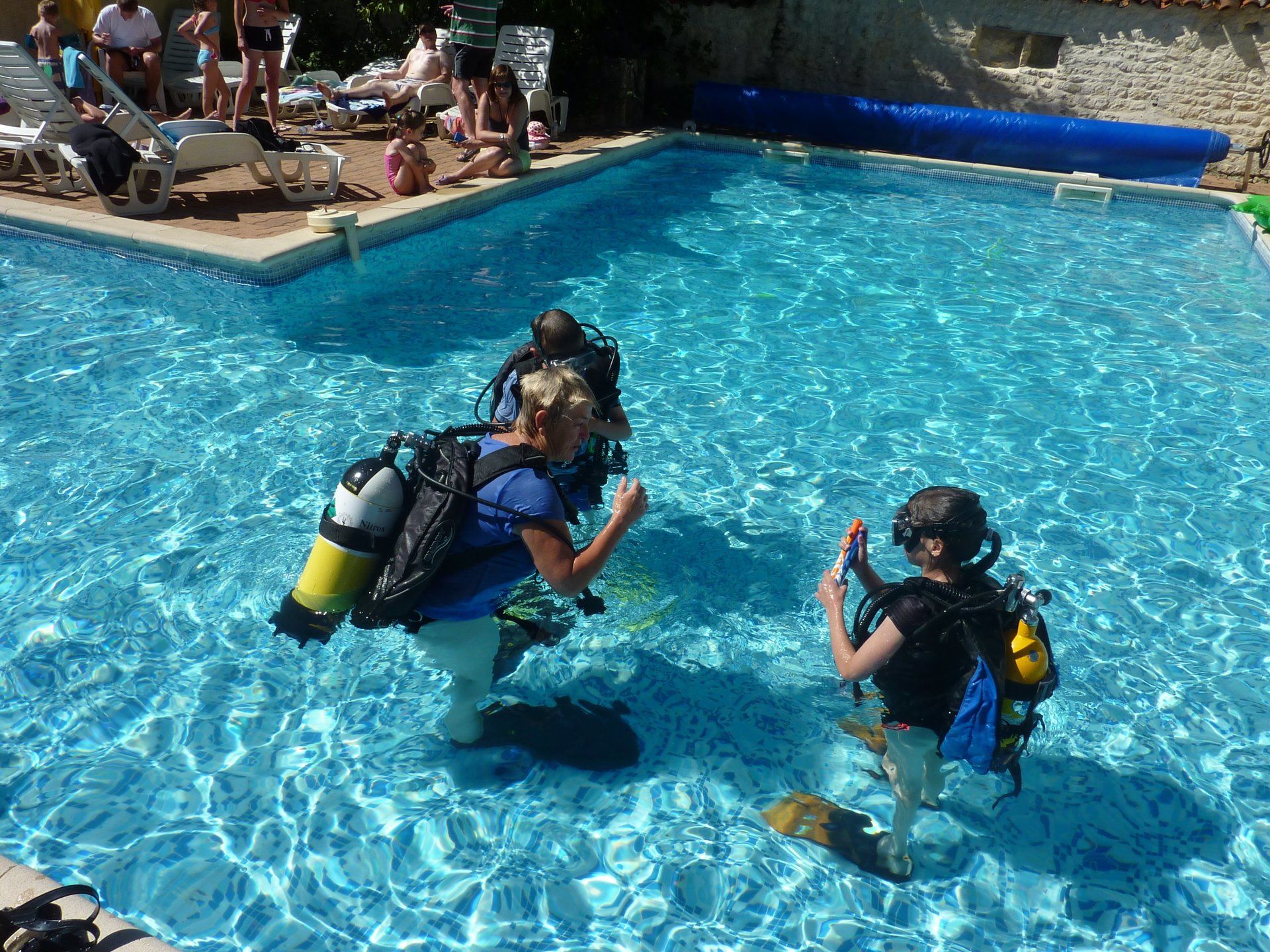 a scuba diving instructor teaching children to scuba dive in a swimming pool