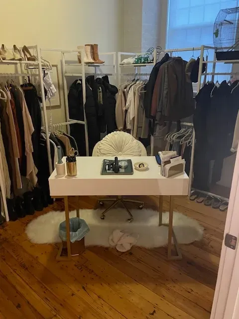 A closet with clothes hanging on racks and a desk in the middle