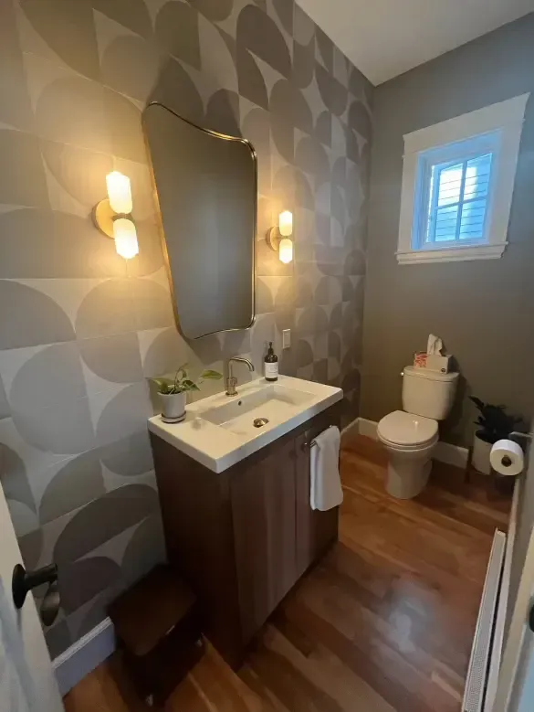 A bathroom with a sink , toilet , mirror and window.