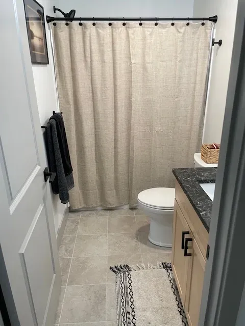 A bathroom with a toilet , sink and shower curtain.