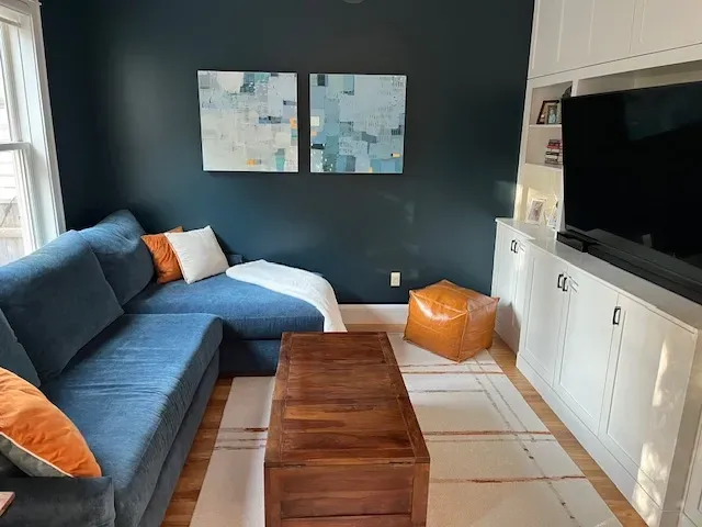 A living room with a blue sectional couch and a wooden coffee table