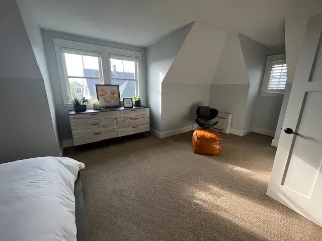 A bedroom with a bed a dresser and a chair