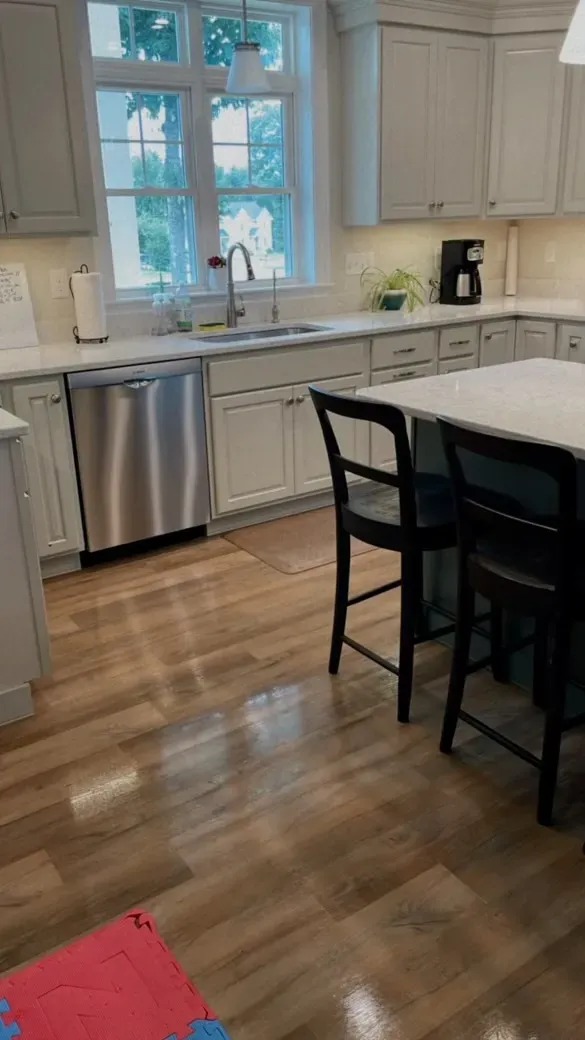 A kitchen with white cabinets , stainless steel appliances , a table and chairs.