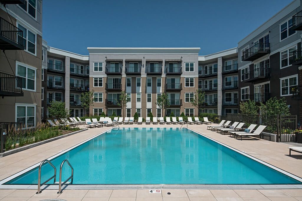 large swimming pool surrounded by lounge chairs outside Marq on Main apartments in Lisle