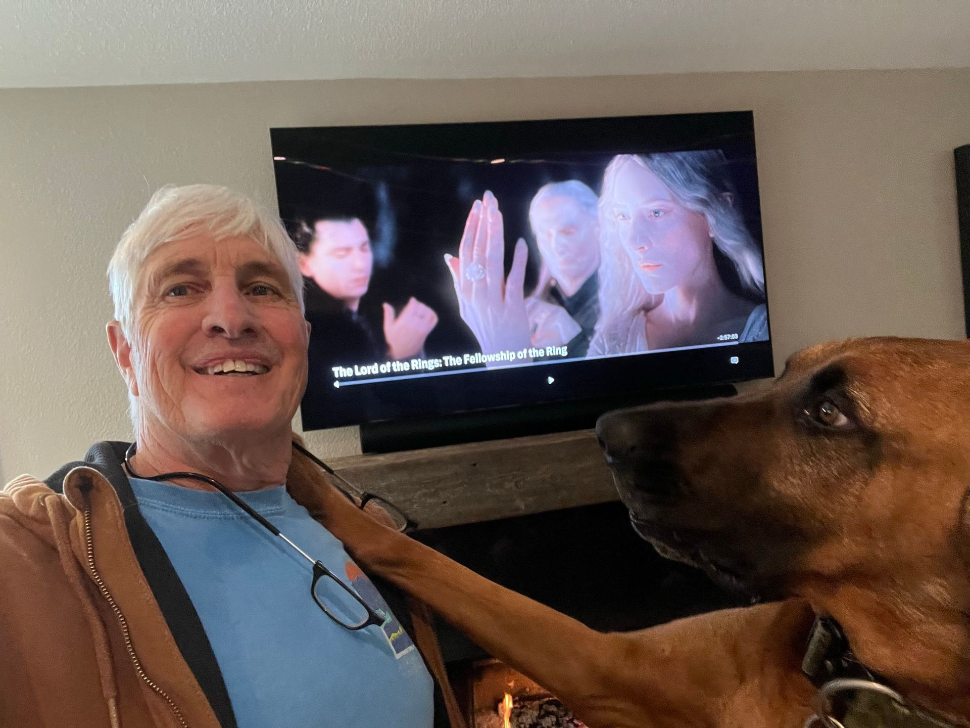 A man and a dog are standing in front of a television.