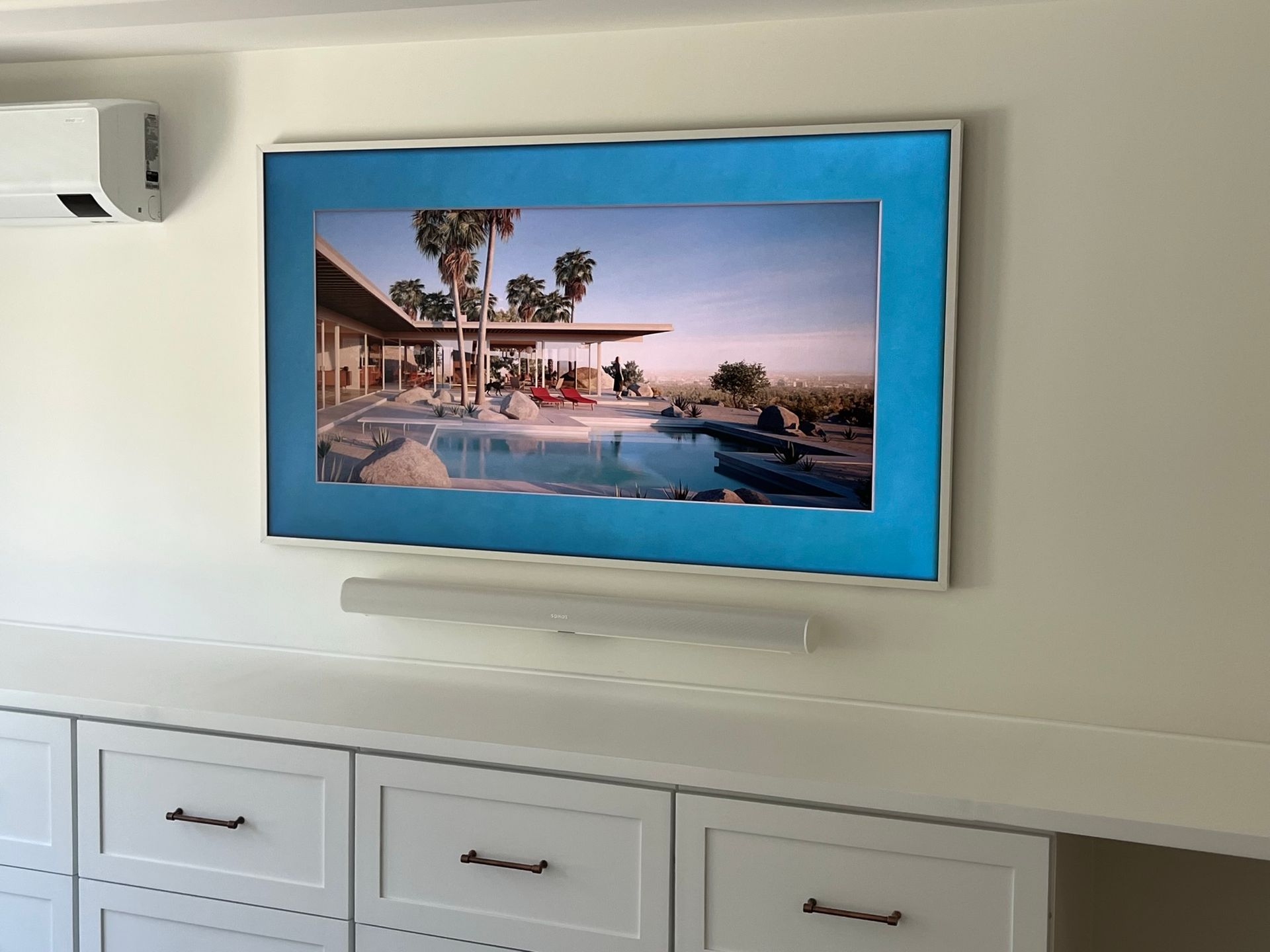 A flat screen tv is hanging on a wall above a dresser.