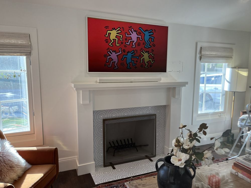 A living room with a fireplace and a painting on the wall.