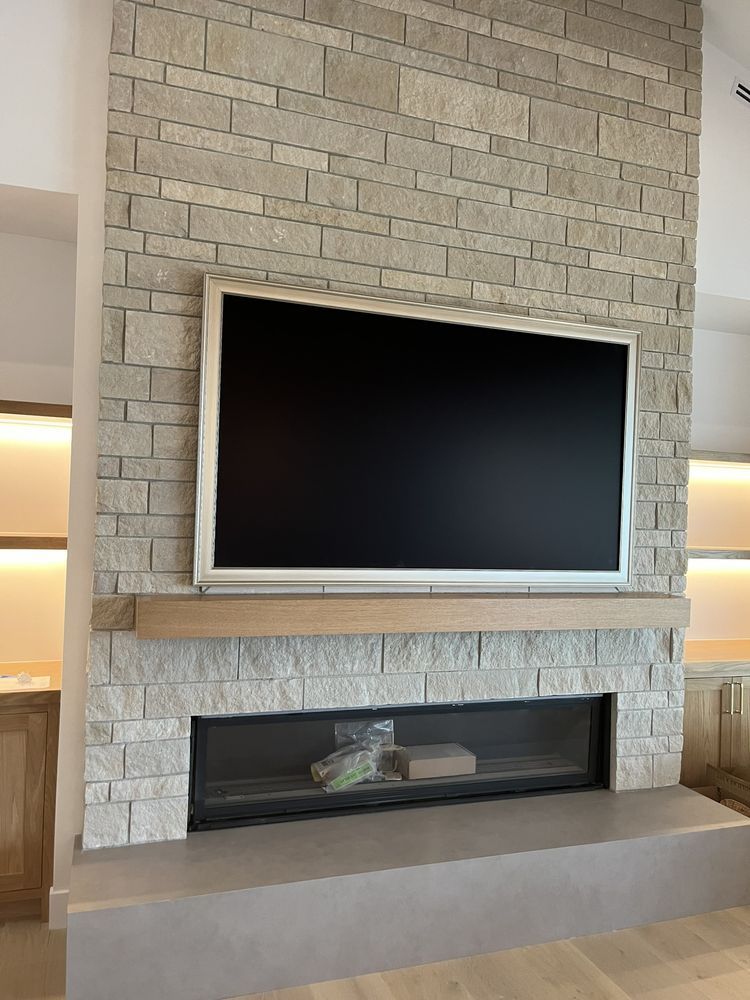 A flat screen tv is mounted on a brick wall above a fireplace.