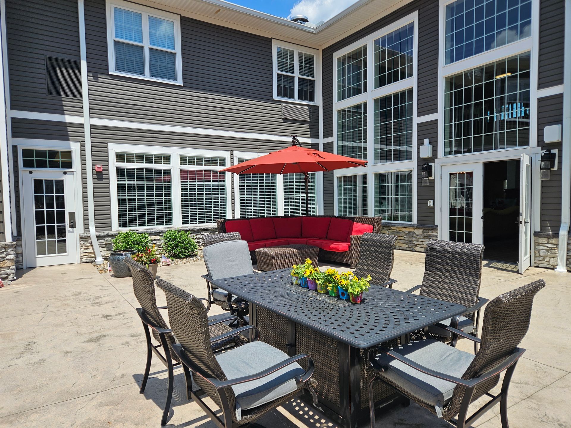 Outdoor patio with seating, umbrella, and building with large windows.