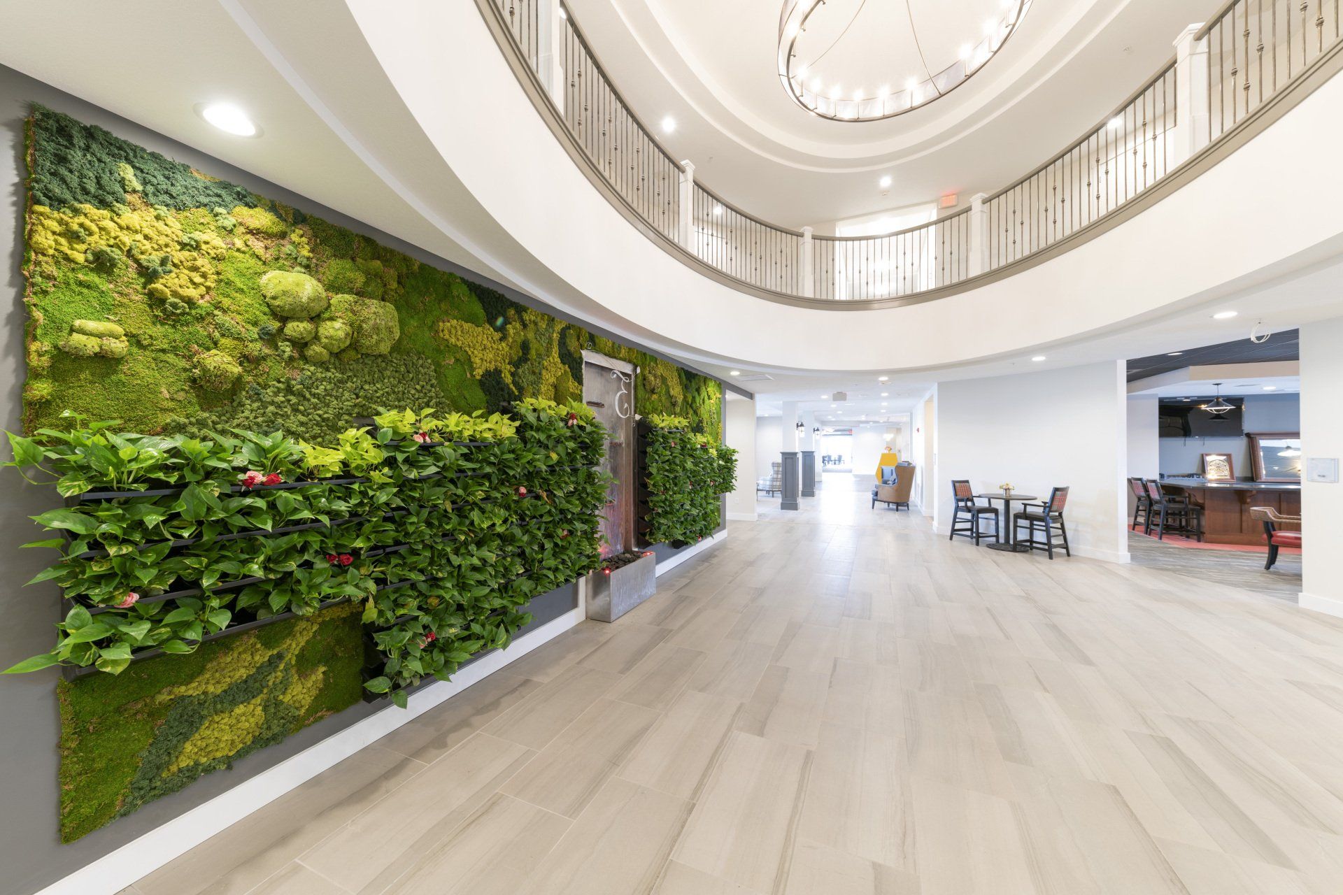 Lobby with a large living wall, balcony, and seating area. Bright, open space with light wood floors and white walls.
