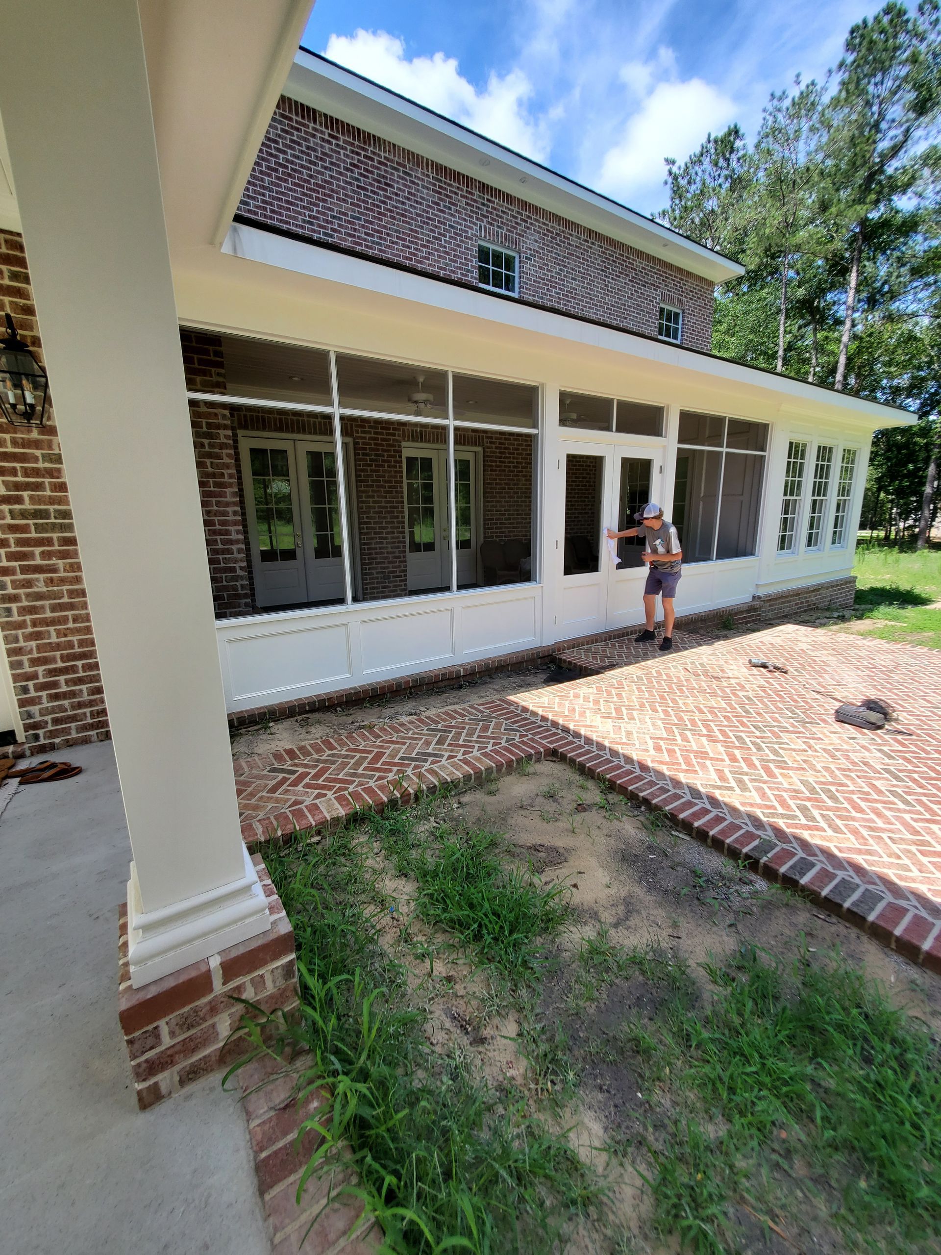Brick home with screened porch; person standing near doorway.
