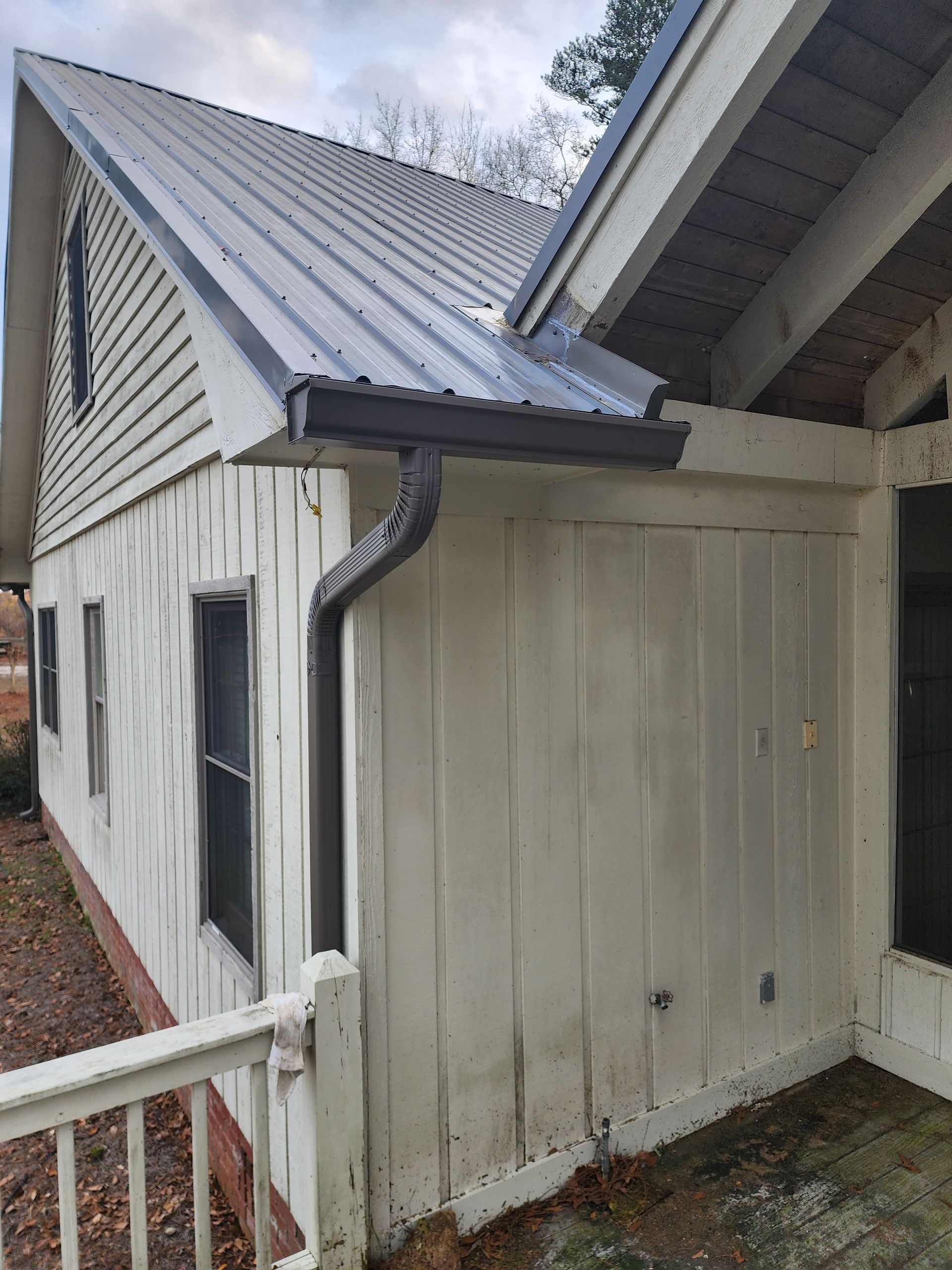 Exterior view of a white building with a metal roof and dark gutters.