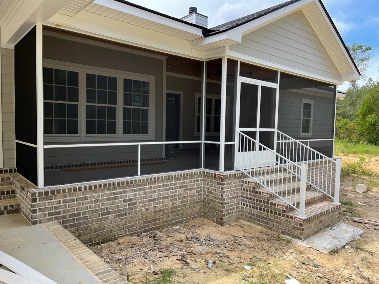 Screened porch with brick base and white railings, steps, and trim.
