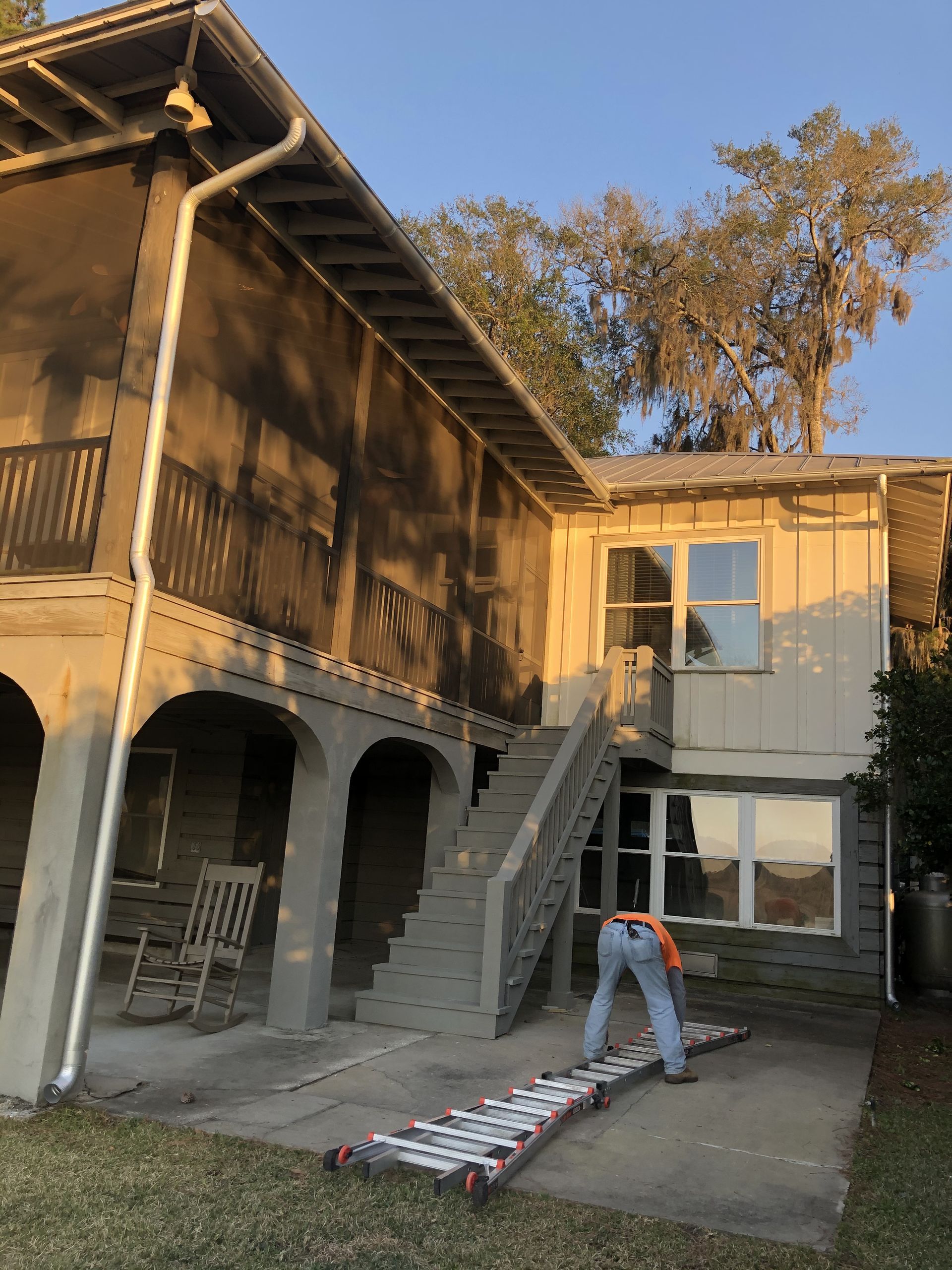 Person on a ramp near a two-story building with a screened porch and stairs.