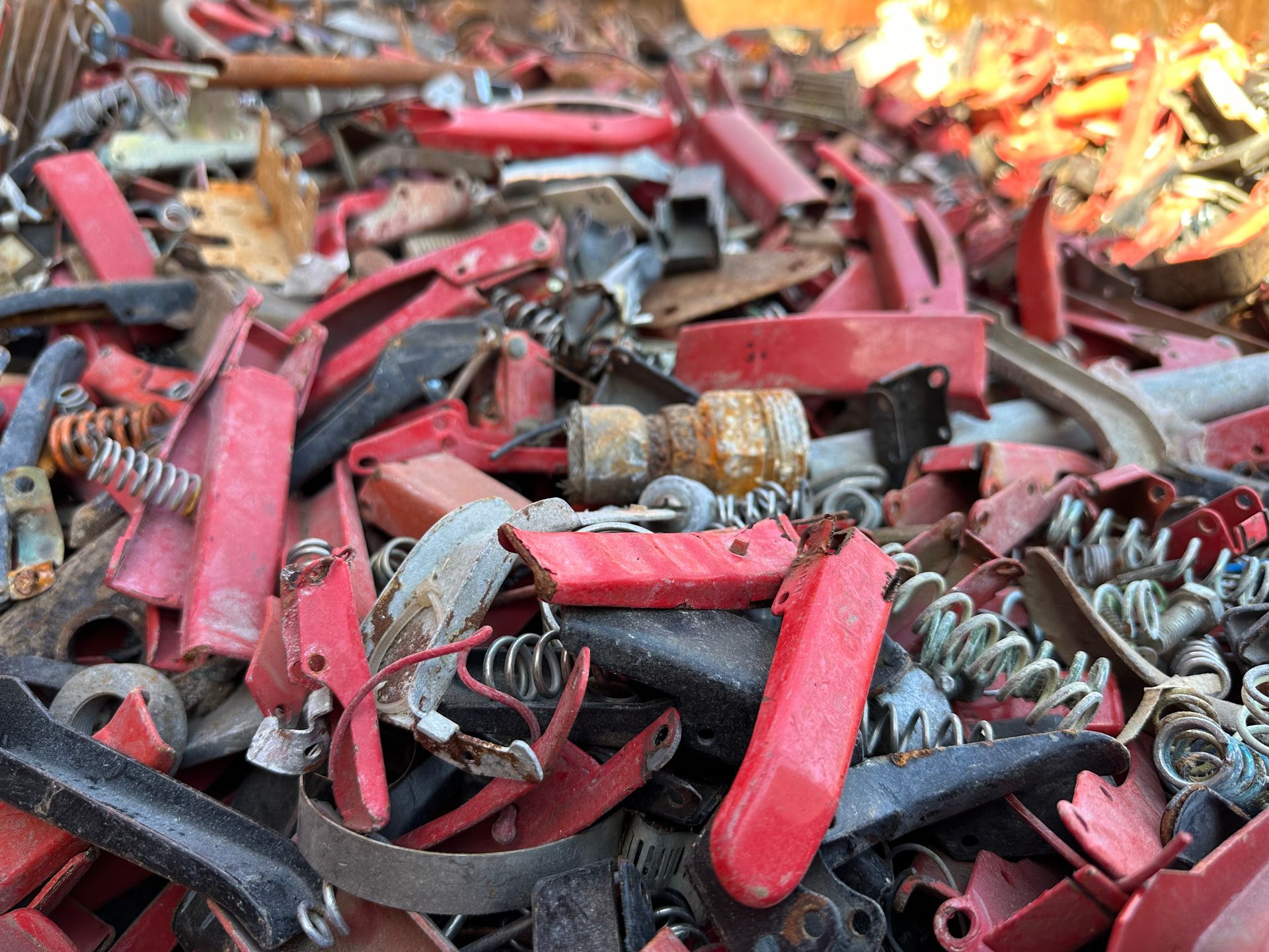 Pile of red and black scrap plastic and metal parts, including springs.