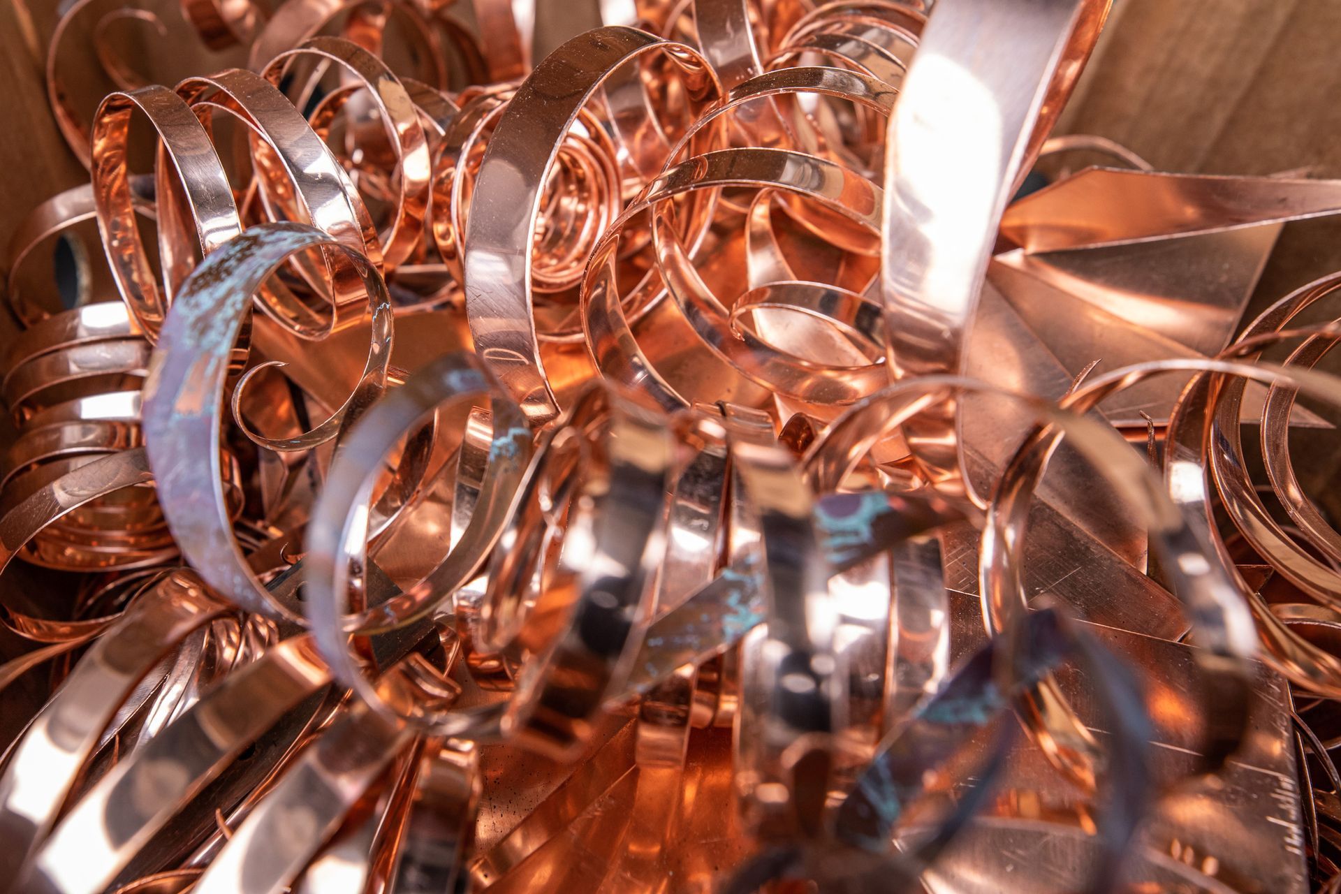 Close-up of a pile of shiny, curling copper strips, possibly scrap metal.