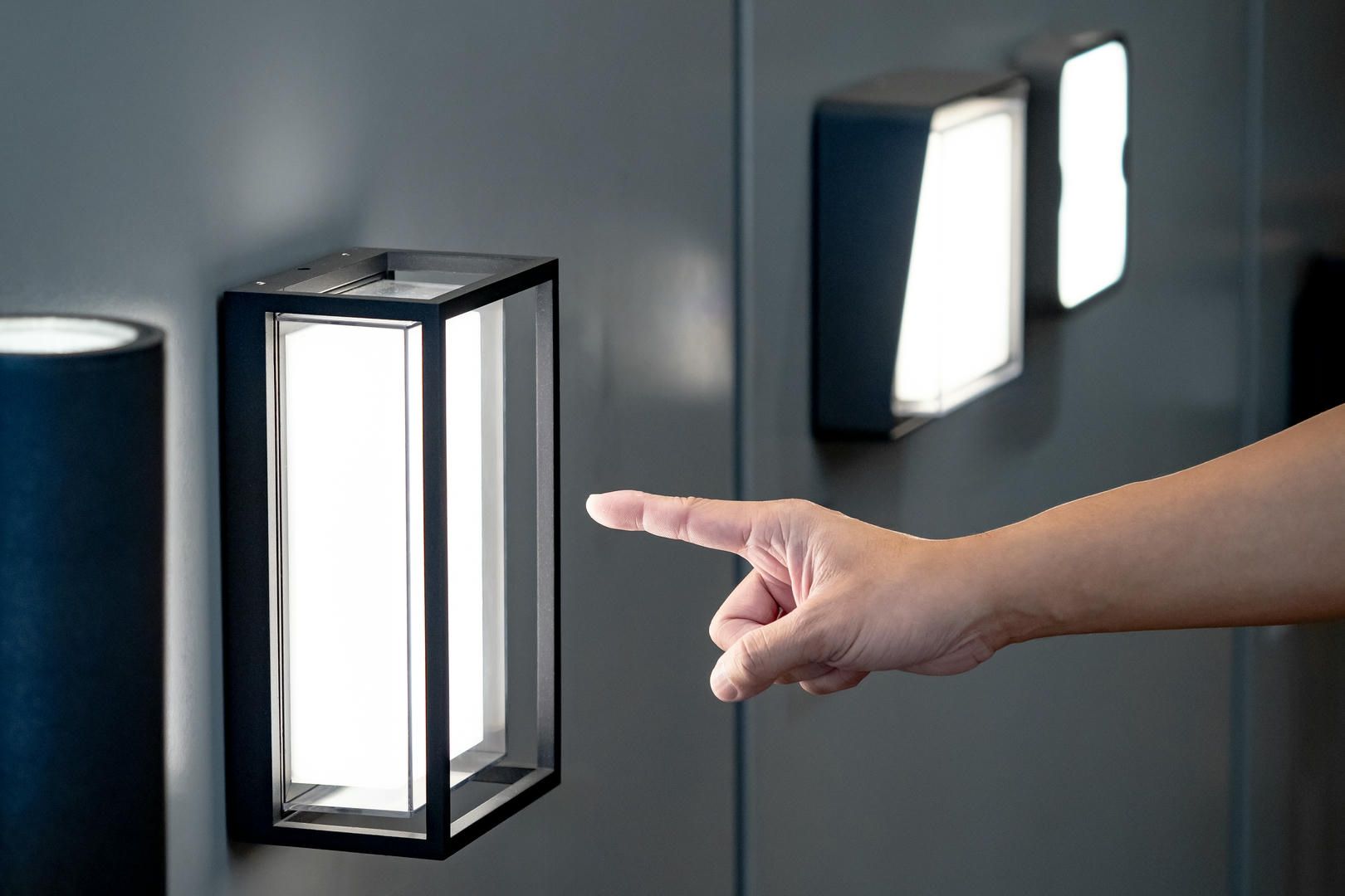 A person is pointing at a light on a wall.