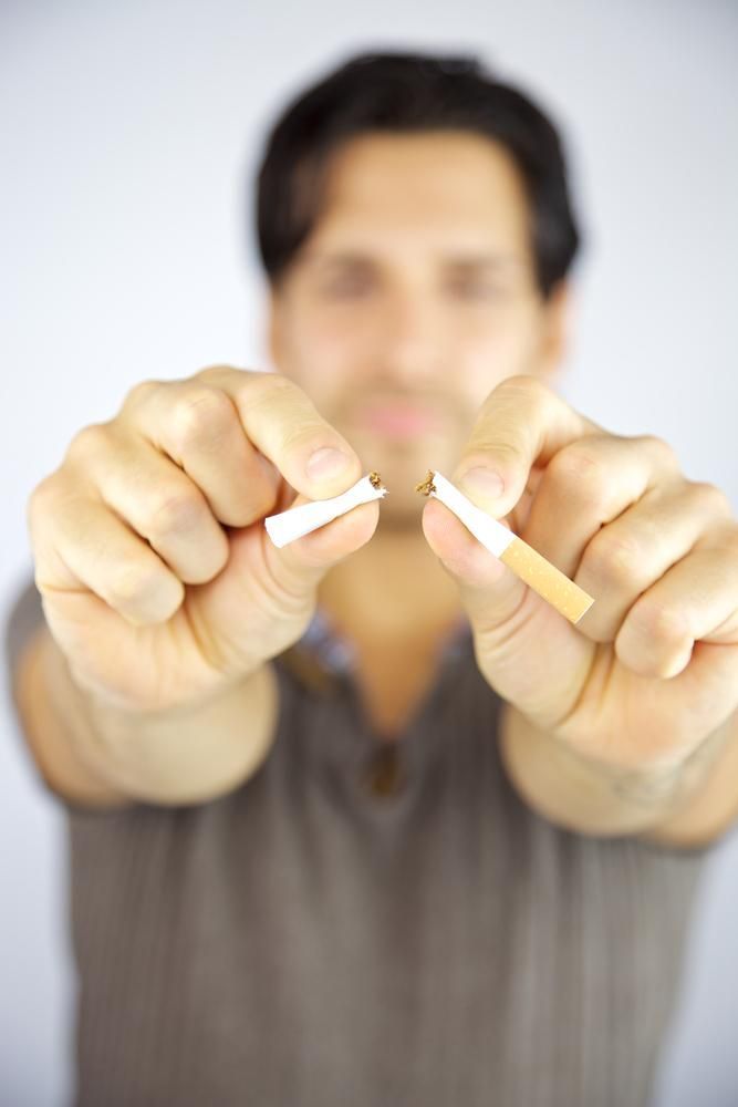 a Man is Holding Two Broken Cigarettes in His Hands — Warners Bay Pharmacy In Warners Bay, NSW