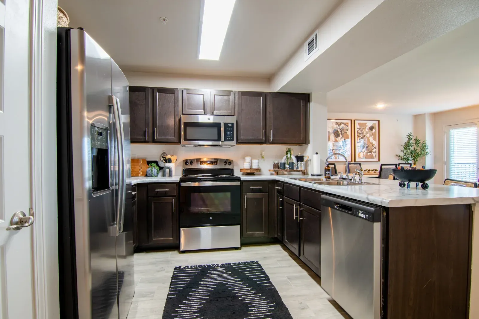 Modern kitchen with dark wood cabinets, stainless steel appliances, and an island.