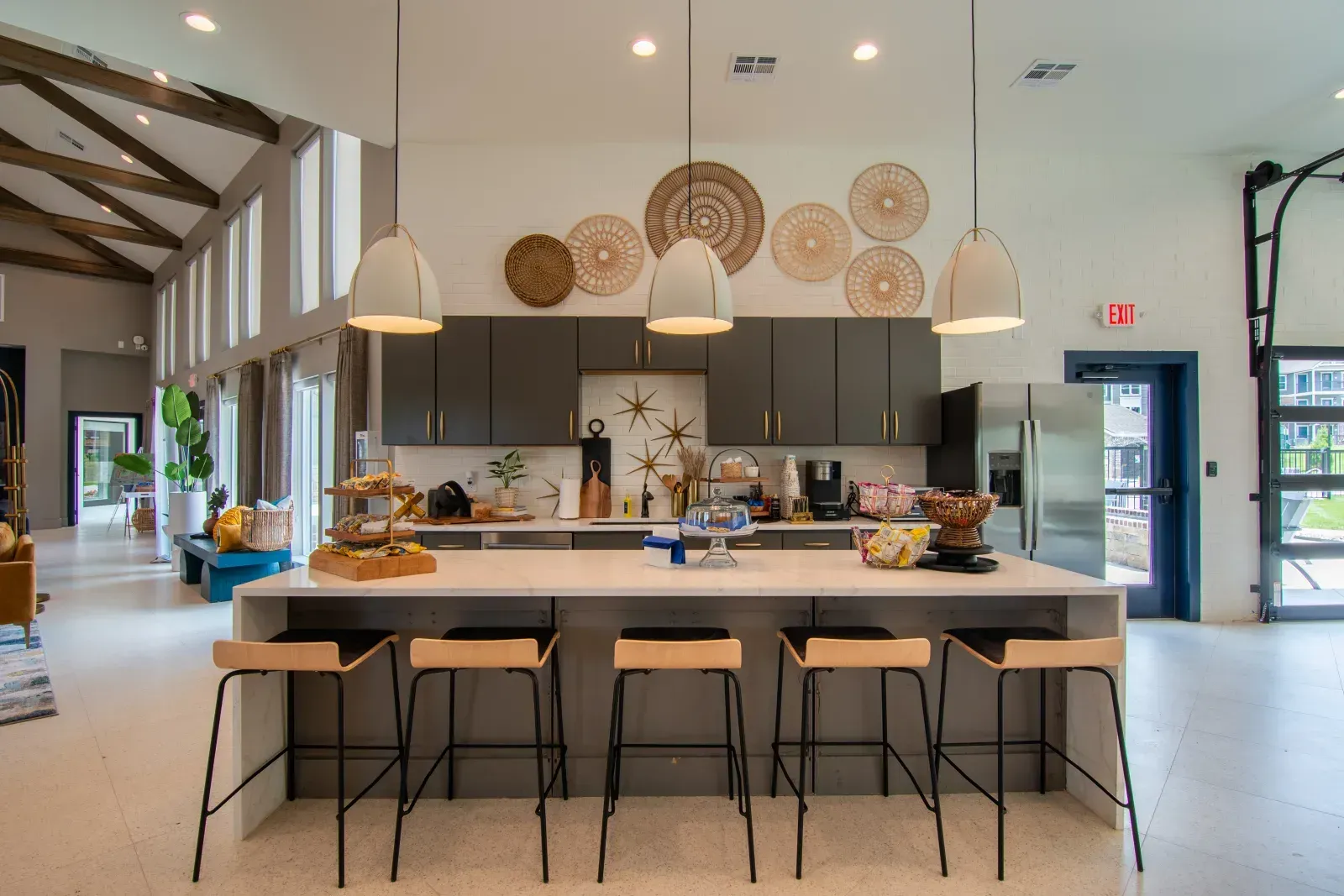 Modern community kitchen with a large island, pendant lights and gray cabinets.