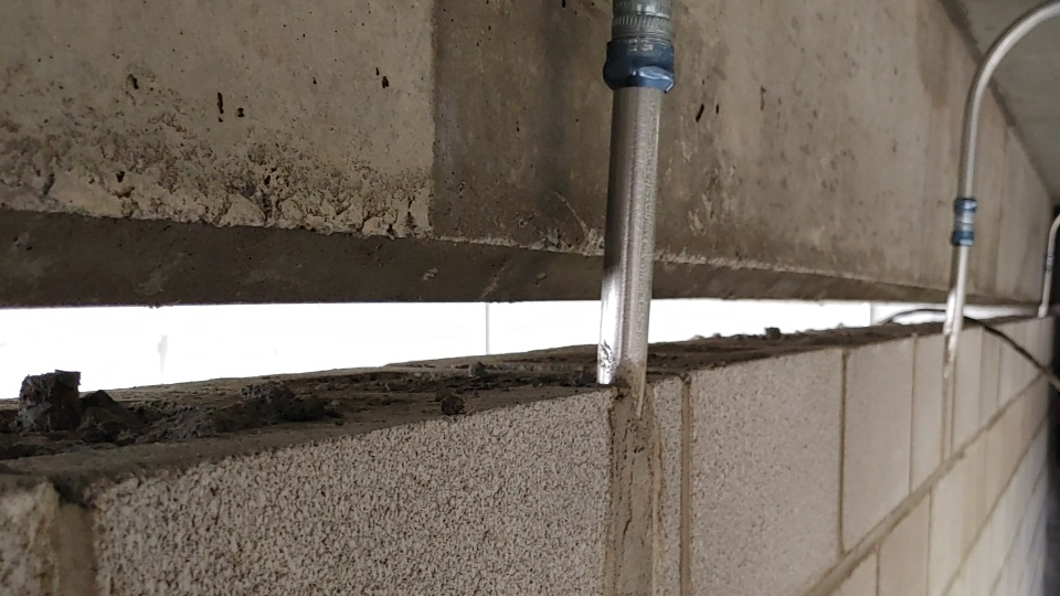 Un gros plan d'un mur de briques avec des tuyaux qui en sortent.
