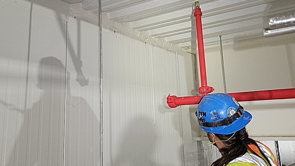 Un ouvrier du bâtiment portant un casque bleu travaille sur un mur.