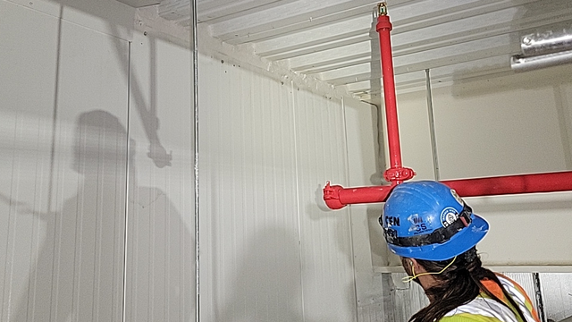 Un ouvrier du bâtiment portant un casque bleu travaille sur un mur.