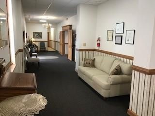 A long hallway with a couch and chairs in it.