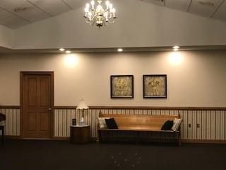 There is a couch in the middle of the room with a chandelier hanging from the ceiling.