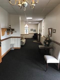 A long hallway with chairs and a chandelier in a church.