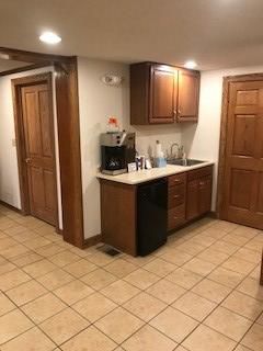 A kitchen with wooden cabinets , a sink , and a dishwasher.