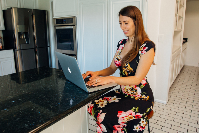 A woman is sitting at a counter using a laptop computer.