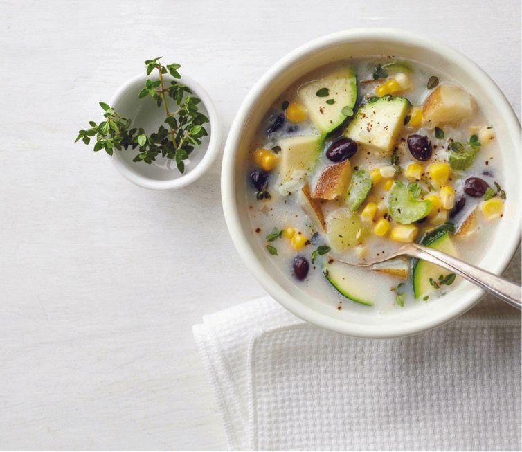 A bowl of soup with vegetables and a spoon in it