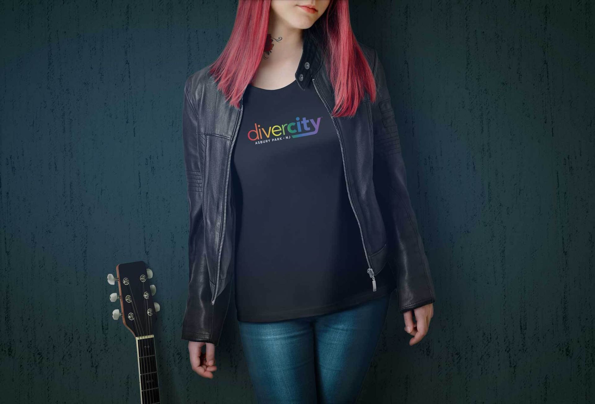 Girl in black leather jacket, long red hair and guitar alongside wearing rainbow divercity Tty logo
