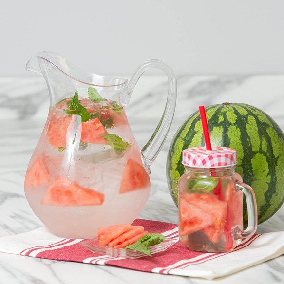 A pitcher of watermelon juice next to a jar of watermelon juice