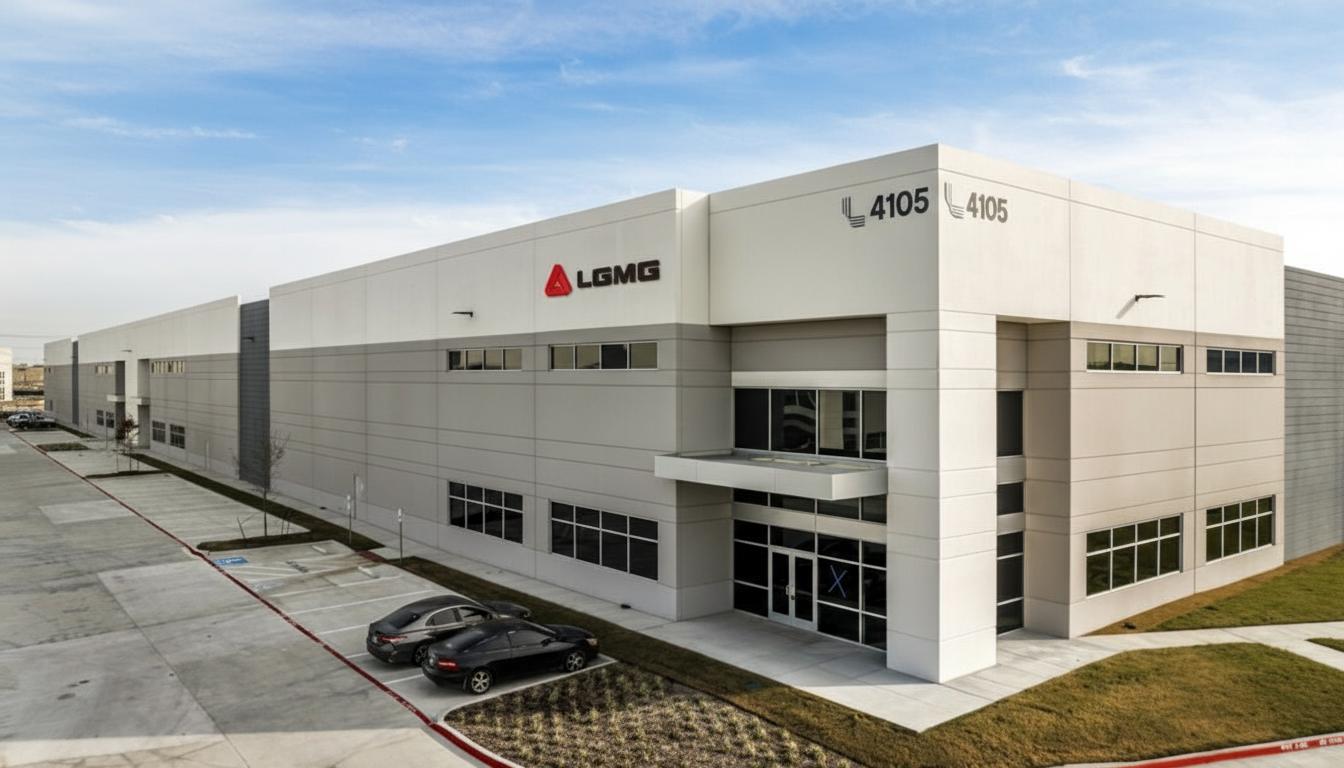Exterior view of a modern warehouse with "Lomas" logo. Gray and white building with parked cars and a clear sky.
