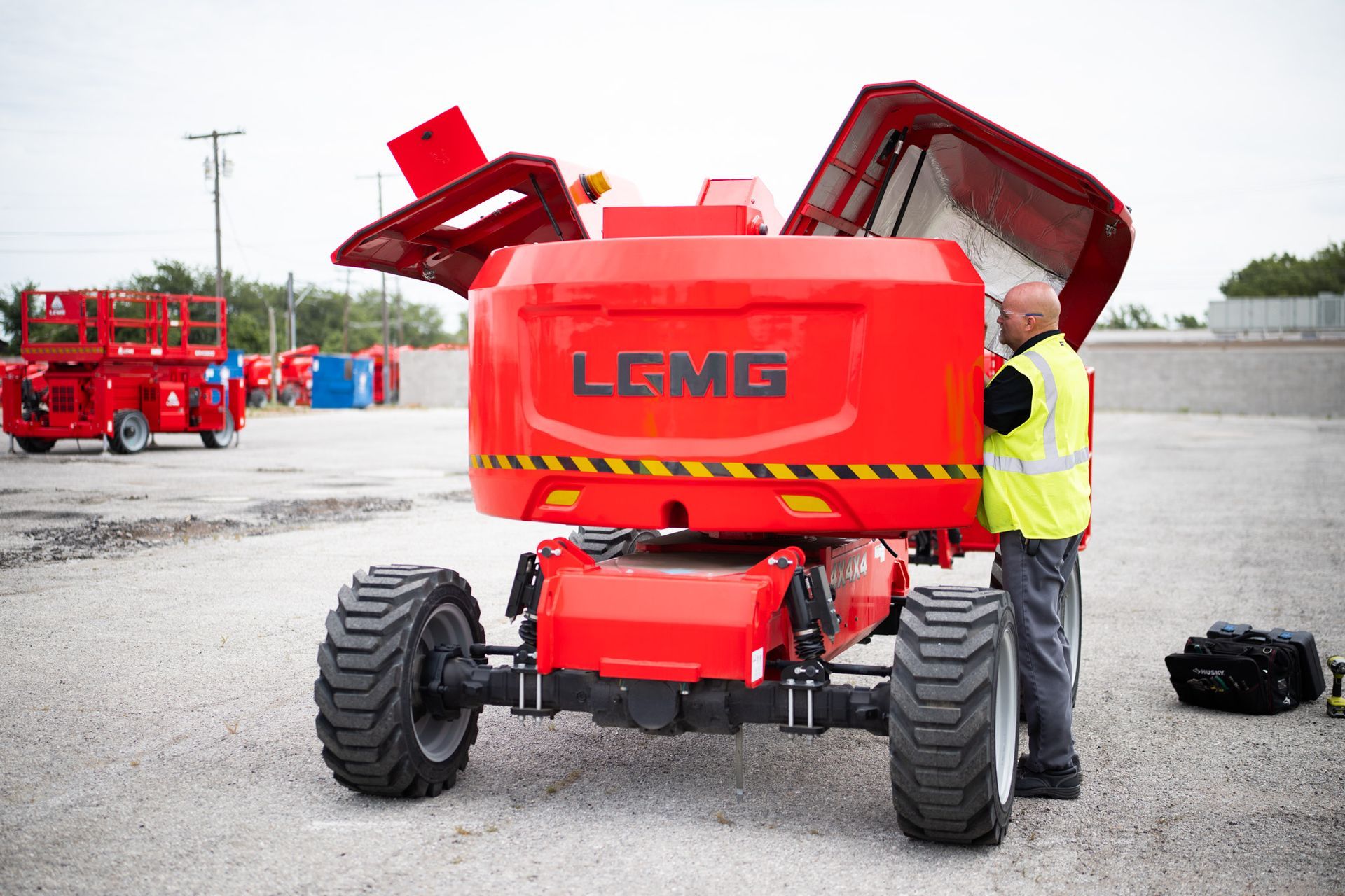 Construction equipment display booth with red machinery, LCMG sign, and people.