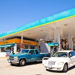 Two cars are parked in front of a gas station.