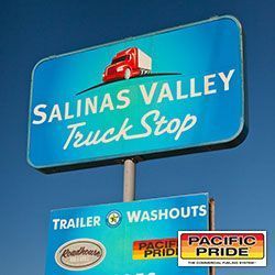 A blue sign for Salinas Valley Truck stop with a red truck on it.